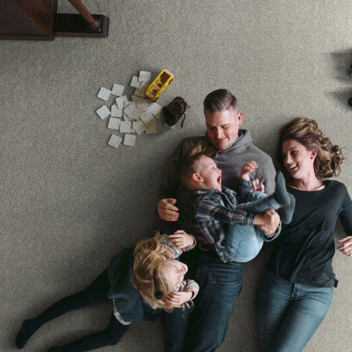 Family laying on carpet - Home Design of Hastings in Hastings, MN