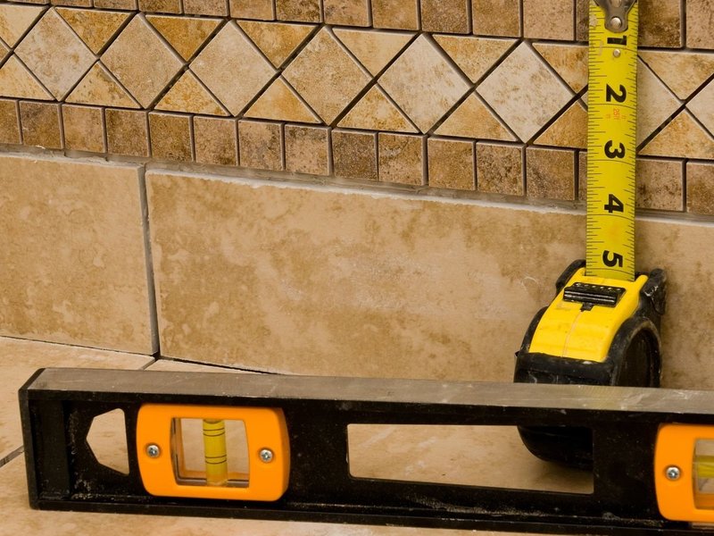 measure tape and level against tile - Home Design of Hastings in Hastings, MN